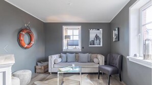 Una sala de estar moderna con un sofá, una mesa de centro de vidrio y un sillón gris.