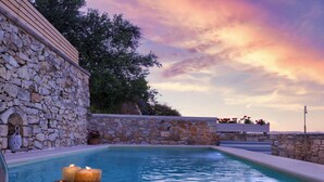 A stone pool with candles, surrounded by a stone wall and a wooden deck. - Cozy Holiday Home With Pool and Whirlpool in Maheri (Apokoronas)