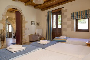 A room with two beds, a stone archway, wooden ceiling beams, a window with striped curtains, and a radiator. - Cozy Holiday Home With Pool and Whirlpool in Maheri (Apokoronas)