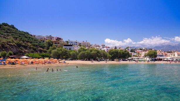 A coastal town with clear waters, beach umbrellas, and buildings along the shore. - Cozy Holiday Home With Pool and Whirlpool in Maheri (Apokoronas)