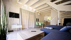 Un salon moderne comprenant un canapé, une table basse et un coin repas avec des chaises.