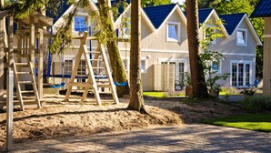 Une rangée de maisons en bois aux toits bleus, une balançoire en bois et un chemin pavé.