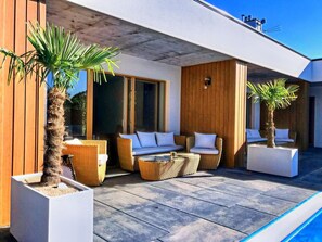 A modern outdoor seating area with wicker furniture and potted palm trees. - House With a Private Swimming Pool and Sauna (Swinoujscie)