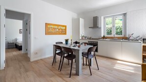 Una cocina moderna con armarios blancos, una mesa de comedor con sillas y un ventanal que aporta luz natural.