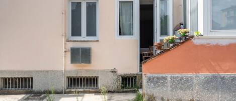 A building with a balcony, a window with a curtain, and a door.
