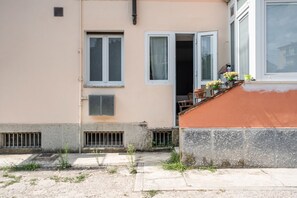 Ein Gebäude mit einem Balkon, einem fensterartigen Öffnung mit Vorhang und einer Tür.