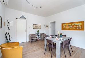 Ein modernes Wohnzimmer mit Essbereich, einer Couch, einem Couchtisch und einem Gemälde an der Wand.