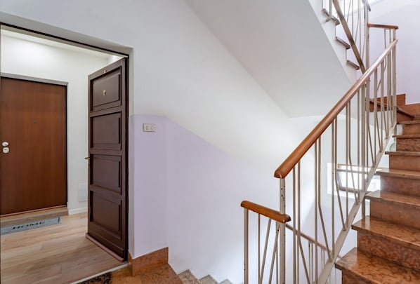 Eine Treppe mit hölzernen Geländern und einem Metallgeländer, die zu einer Zwischenebene mit einer Tür führt.
