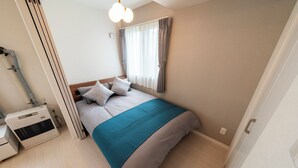 A bedroom with a bed, a heater, a window with curtains, and a door. - UTOPIA 101 (Sapporo)