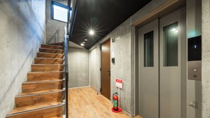 Ein modernes Interieur mit einer Holztreppe, grauen Wänden und einem Feuerlöscher.