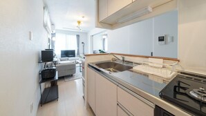 Eine moderne Küche mit Einbauherd, Spüle und Essbereich inklusive Sofa und Fernseher.
