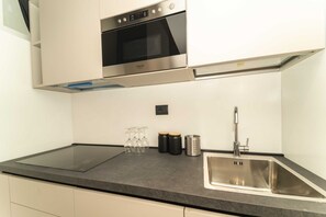 Réfrigérateur, un four, surface de cuisson, vaisselle et ustensiles