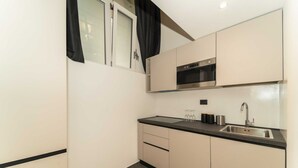 A compact kitchen with a microwave, oven, sink, and cabinets. - GuestHost - Galaxy Lofts - Appt Jupiter x4 (Torino)