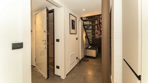 A hallway with a door, a framed picture, a staircase, and a light fixture. - GuestHost - Galaxy Lofts - Appt Jupiter x4 (Torino)
