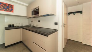 A modern kitchen with a black countertop, stainless steel appliances, and a white brick wall.
