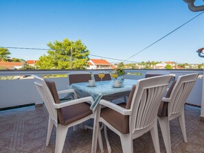 Una terraza con una mesa y sillas, vistas a casas y cielo despejado.