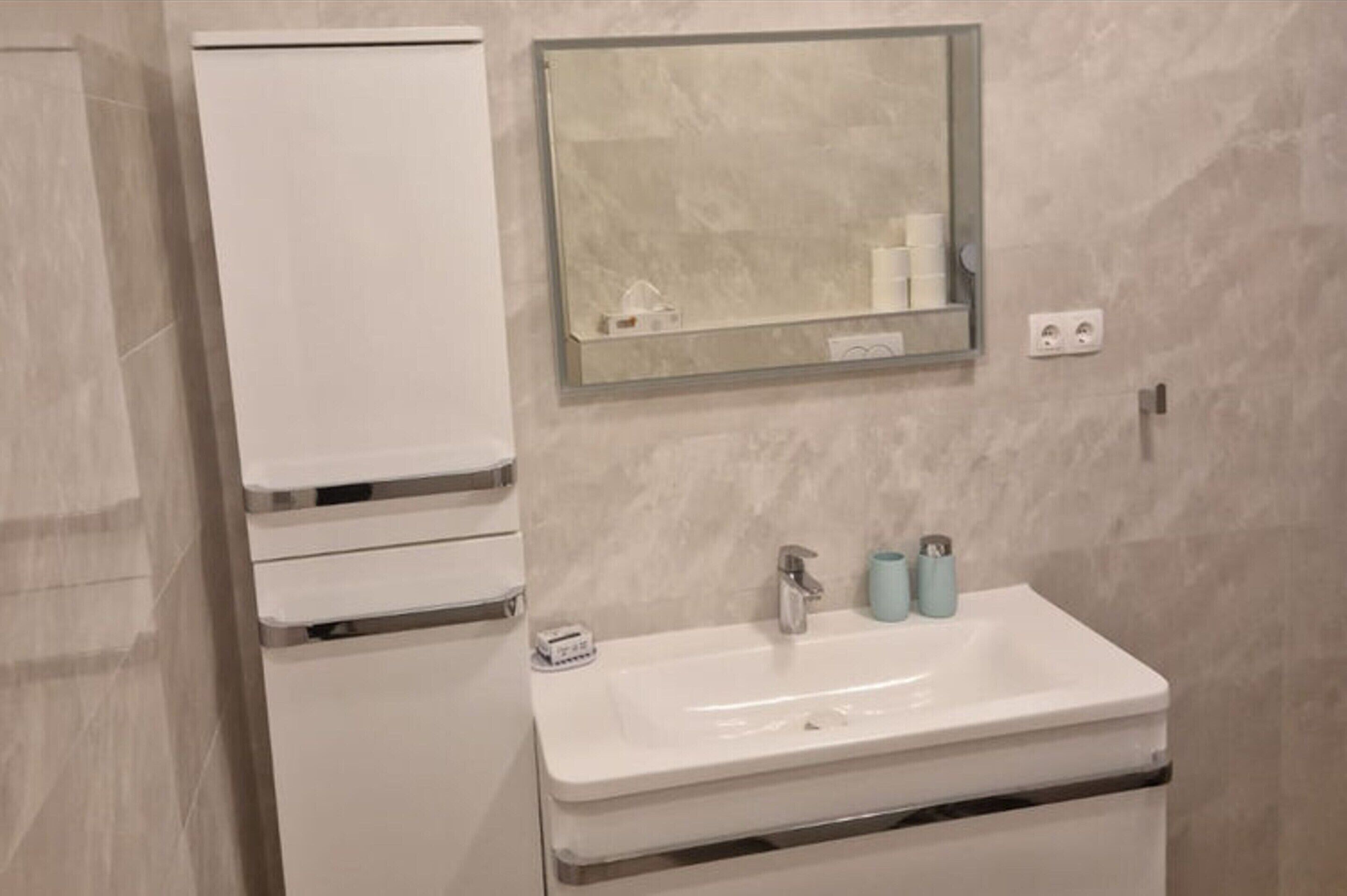A bathroom with a white sink, a mirror, and a cabinet.