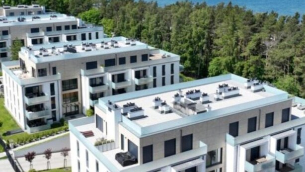 A modern apartment building with multiple balconies, a flat roof, and a view of a forested area. - Apartment Near Baltic Sea With Balcony View (Rewal)