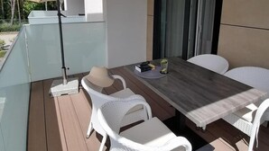 A modern outdoor dining area with a glass-top table, white wicker chairs, and a large umbrella. - Apartment Near Baltic Sea With Balcony View (Rewal)