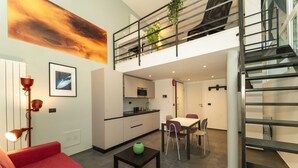 A modern interior with a red sofa, a dining table, a kitchen, and a staircase. - GuestHost - Galaxy Lofts - Appt Uranus x4 (Torino)