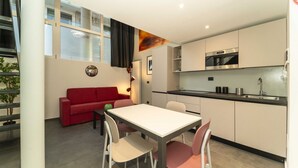 A modern kitchen with a dining area, a red sofa, and a staircase. - GuestHost - Galaxy Lofts - Appt Uranus x4 (Torino)
