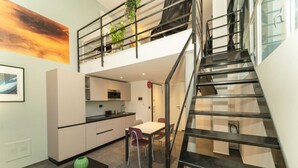 A modern kitchen with a dining area, a staircase, and a view of the sky. - GuestHost - Galaxy Lofts - Appt Uranus x4 (Torino)