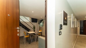 A modern interior with a dining area, staircase, and a hallway leading to a bathroom. - GuestHost - Galaxy Lofts - Appt Saturn x4 (Torino)