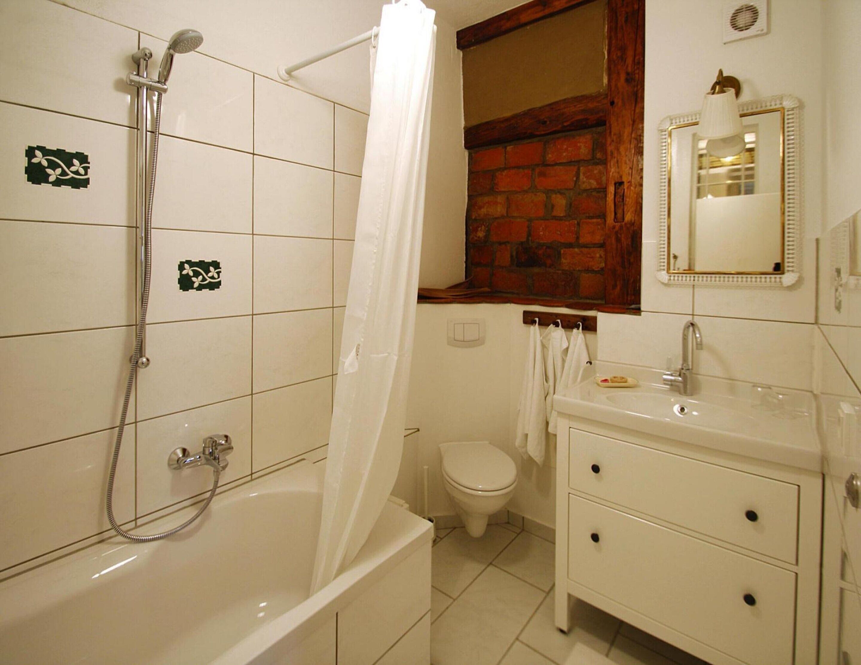 A bathroom with a bathtub, shower, toilet, and a vanity with a mirror.