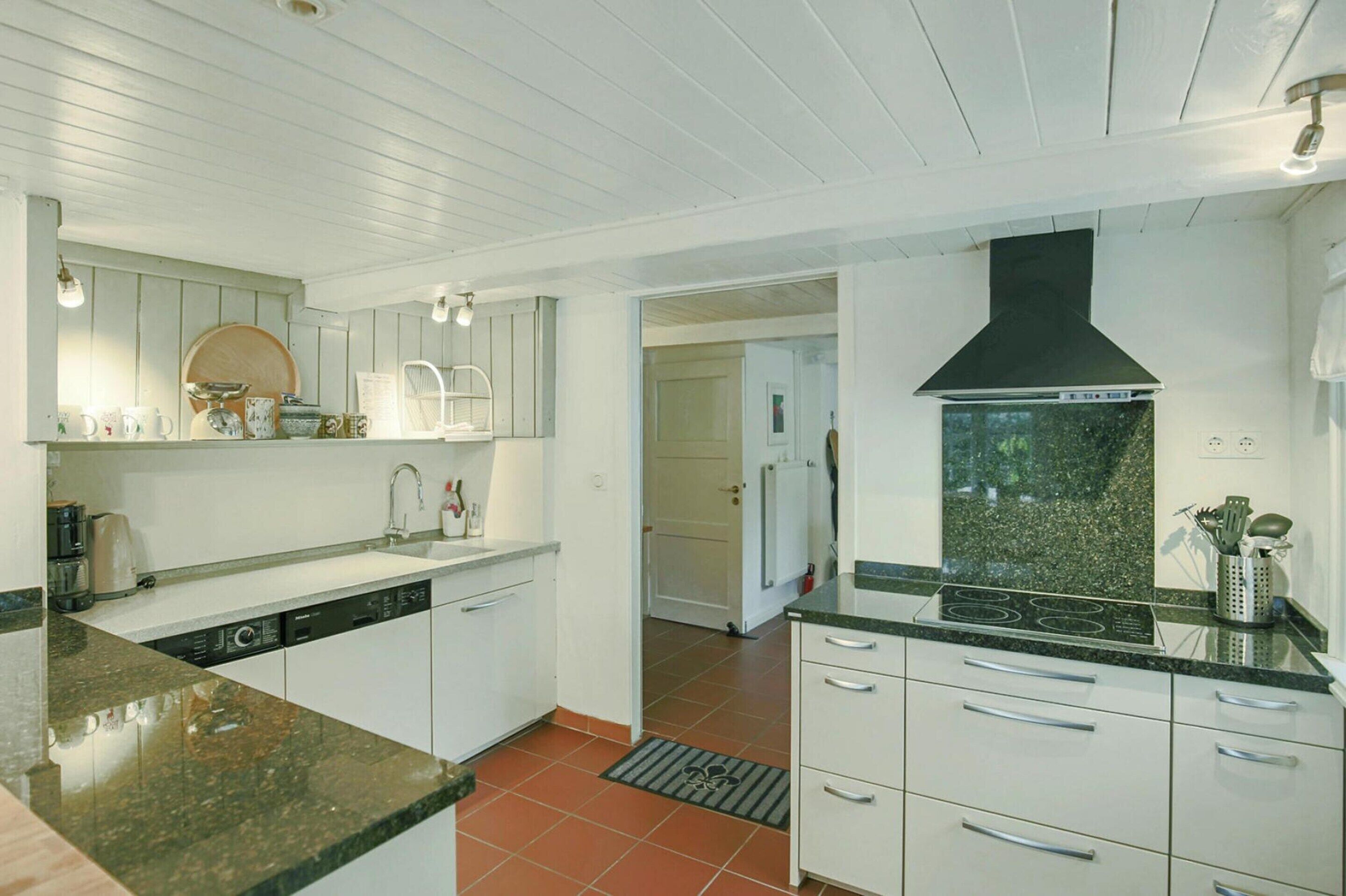 A kitchen with white cabinets, a black stove, and a tiled floor.