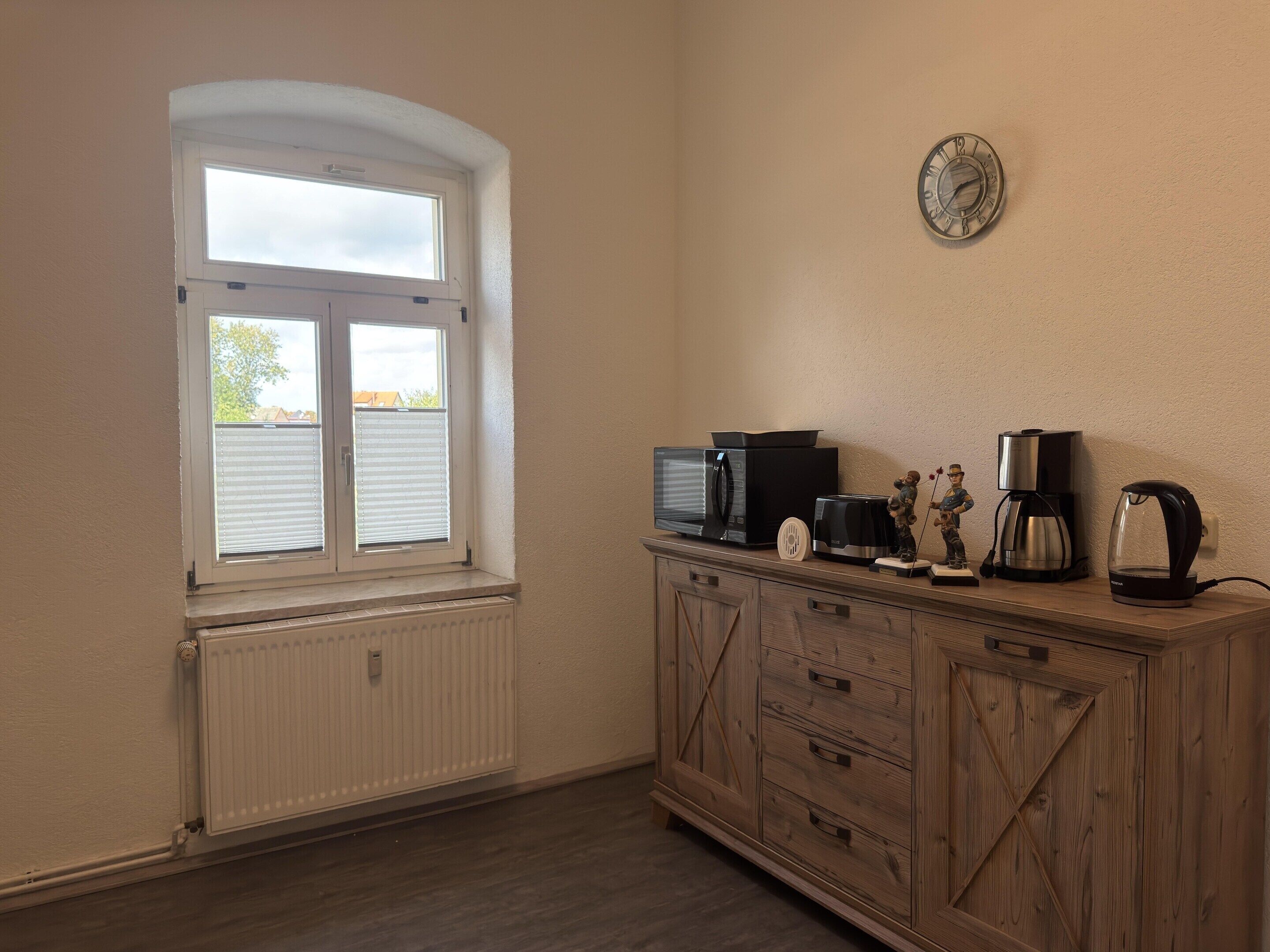A kitchen with a window, a microwave, a coffee maker, and a cabinet.