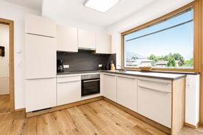 Una cocina moderna con armarios blancos, horno empotrado y un amplio ventanal con vistas al exterior.
