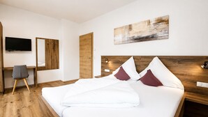 Habitación de hotel con cama, escritorio, silla, televisión y un cuadro en la pared.