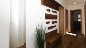 Un pasillo con vigas de madera y un banco, que conduce a una habitación con ventana.