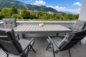 Un patio con una mesa y dos sillas, con vista a un paisaje montañoso.