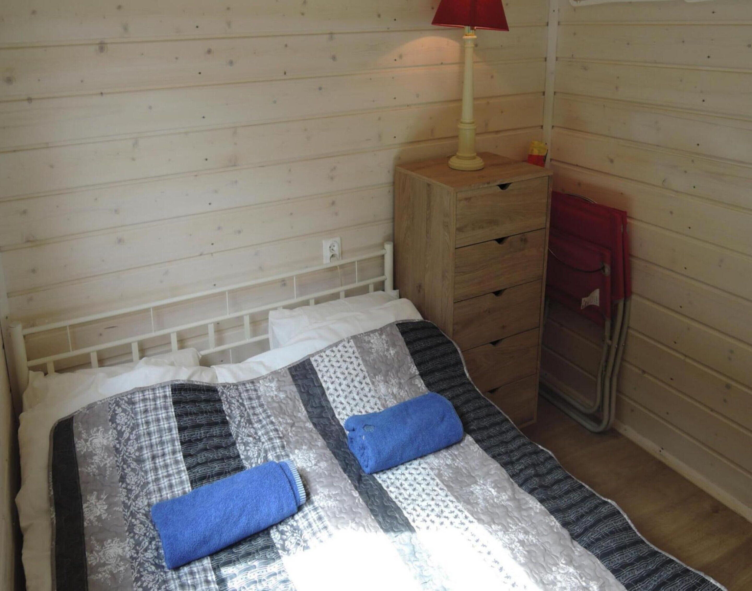 Une petite chambre accueillante, avec un lit simple, une commode en bois et une lampe rouge.