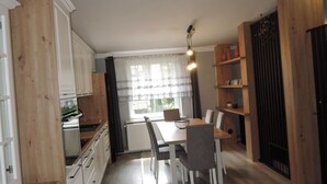 Cozinha moderna com armários de madeira, uma mesa de jantar com cadeiras e iluminação pendente.