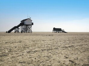 Une plage avec deux constructions en bois, l’une dotée d’un escalier et l’autre d’un toit plat.