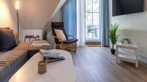 A modern living room with a sofa, a chair, a coffee table, a TV, and a window with curtains. - Ferienwohnung in St. Peter-ording (St. Peter-Ording)