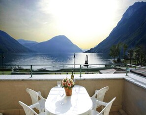 Eine Terrasse mit Tisch und Stühlen mit Blick auf einen See und Berge im Hintergrund.