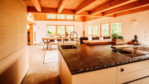 A modern kitchen with a large island, wooden beams, and large windows. - Hideway Chalet Gamsgluck With Pool and Sauna (Waidring)