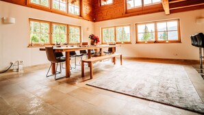 A spacious room with a wooden ceiling, large windows, a long table with chairs, and a rug on the floor. - Hideway Chalet Gamsgluck With Pool and Sauna (Waidring)