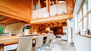 A spacious wooden interior with a dining area, kitchen, and a balcony. - Hideway Chalet Gamsgluck With Pool and Sauna (Waidring)