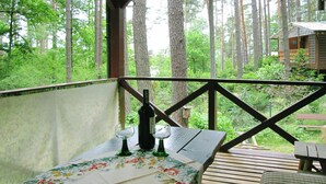 A wooden deck with a table set for two, overlooking a forested area. - Fenced Cottage in the Middle of Nature, Right by the Lake, Rentyny (Gietrzwald)