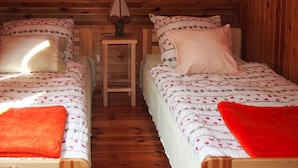 A cabin with two wooden beds, each with a floral-patterned bedspread and pillows. - Fenced Cottage in the Middle of Nature, Right by the Lake, Rentyny (Gietrzwald)