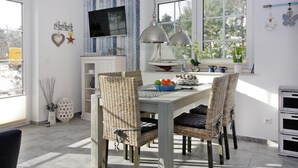 A dining area with wicker chairs, a white table, and a sailboat decoration. - Doppelhaushalfte Dock No. 7.0 in Zirchow (Zirchow)