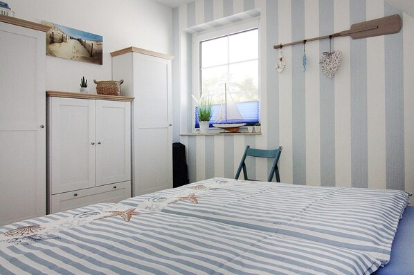 A bedroom with a bed, a window with a view, a chair, and a cabinet. - Doppelhaushalfte Dock No. 7.0 in Zirchow (Zirchow)