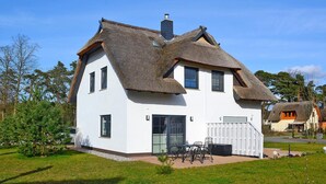 A white house with a thatched roof, a front door, and a small patio with chairs. - Doppelhaushalfte Dock No. 7.0 in Zirchow (Zirchow)
