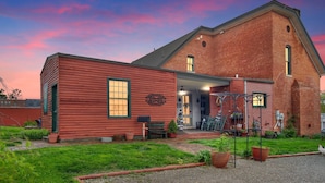 A red brick building with a large open front porch and a small attached shed.