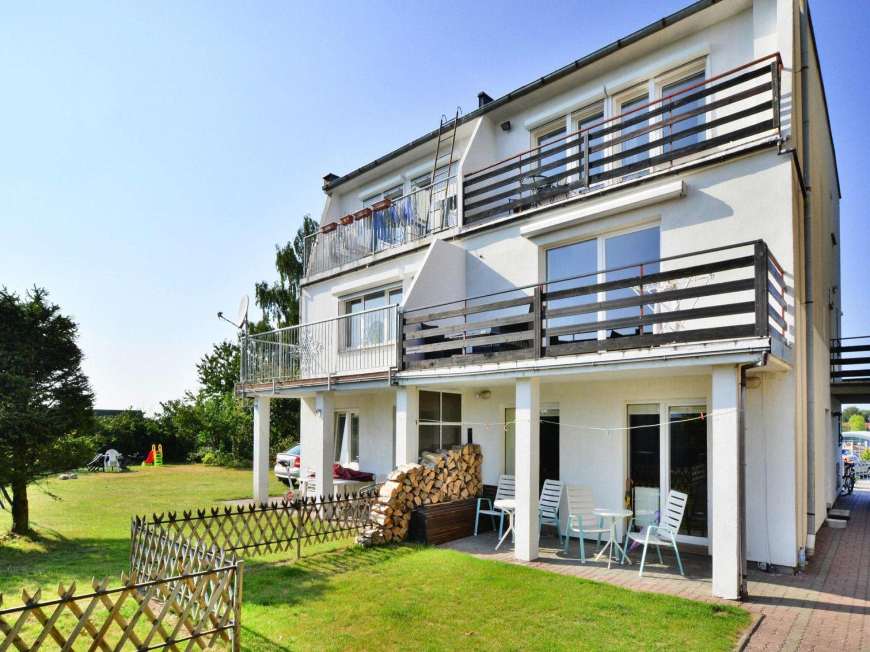 A two-story building with a balcony, outdoor seating area, and a fenced yard.
