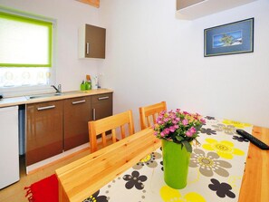 A compact kitchen with a dining table, chairs, and a vase with flowers. - Two-story Holiday Homes Close to the Beach (Mielno)